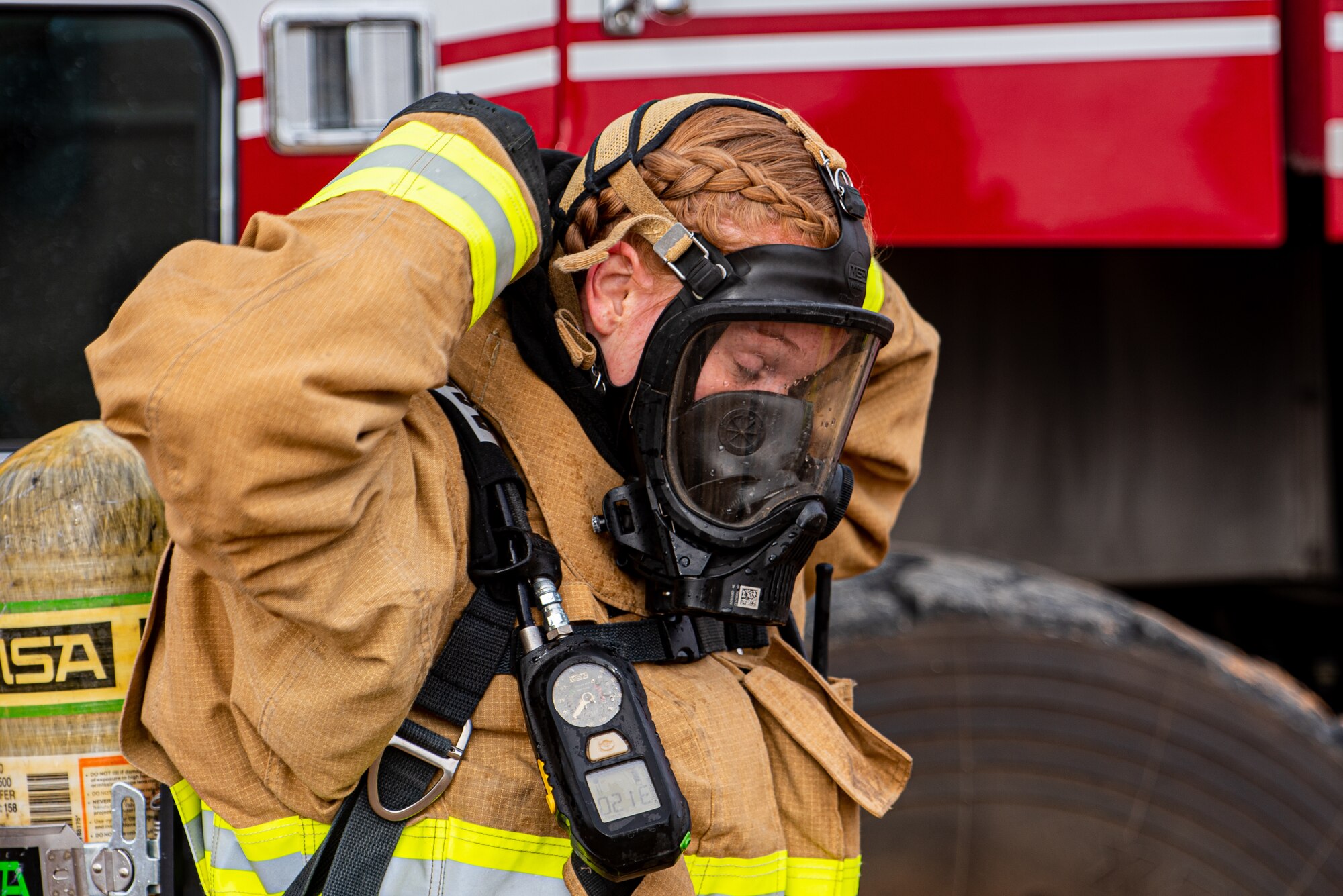 A female firefighter putting on headgear.