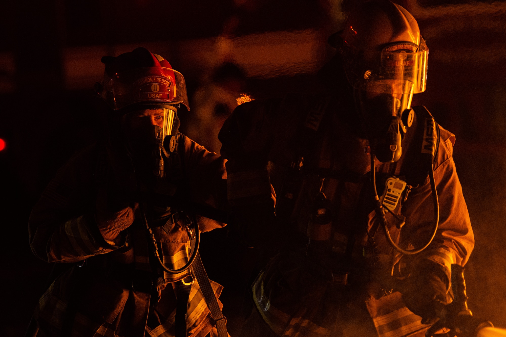 Two firefighters preparing to put out a fire at night.