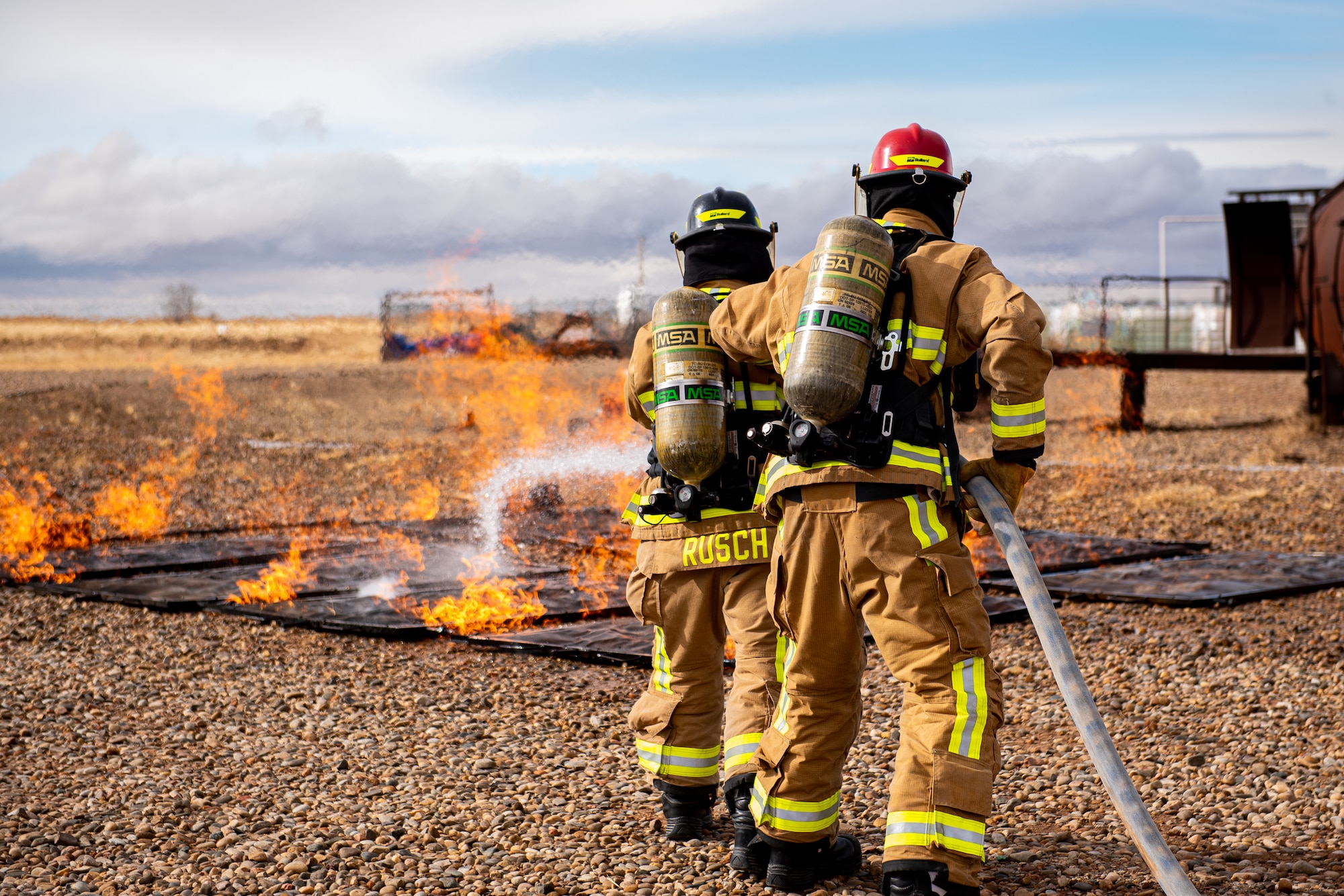 Two firefighters are spraying water at a fire.