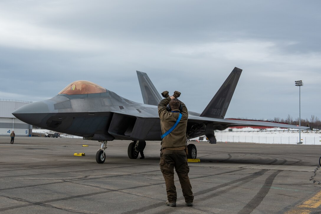 A photo of a U.S. Airman marshaling an F-22 Raptor pilot.