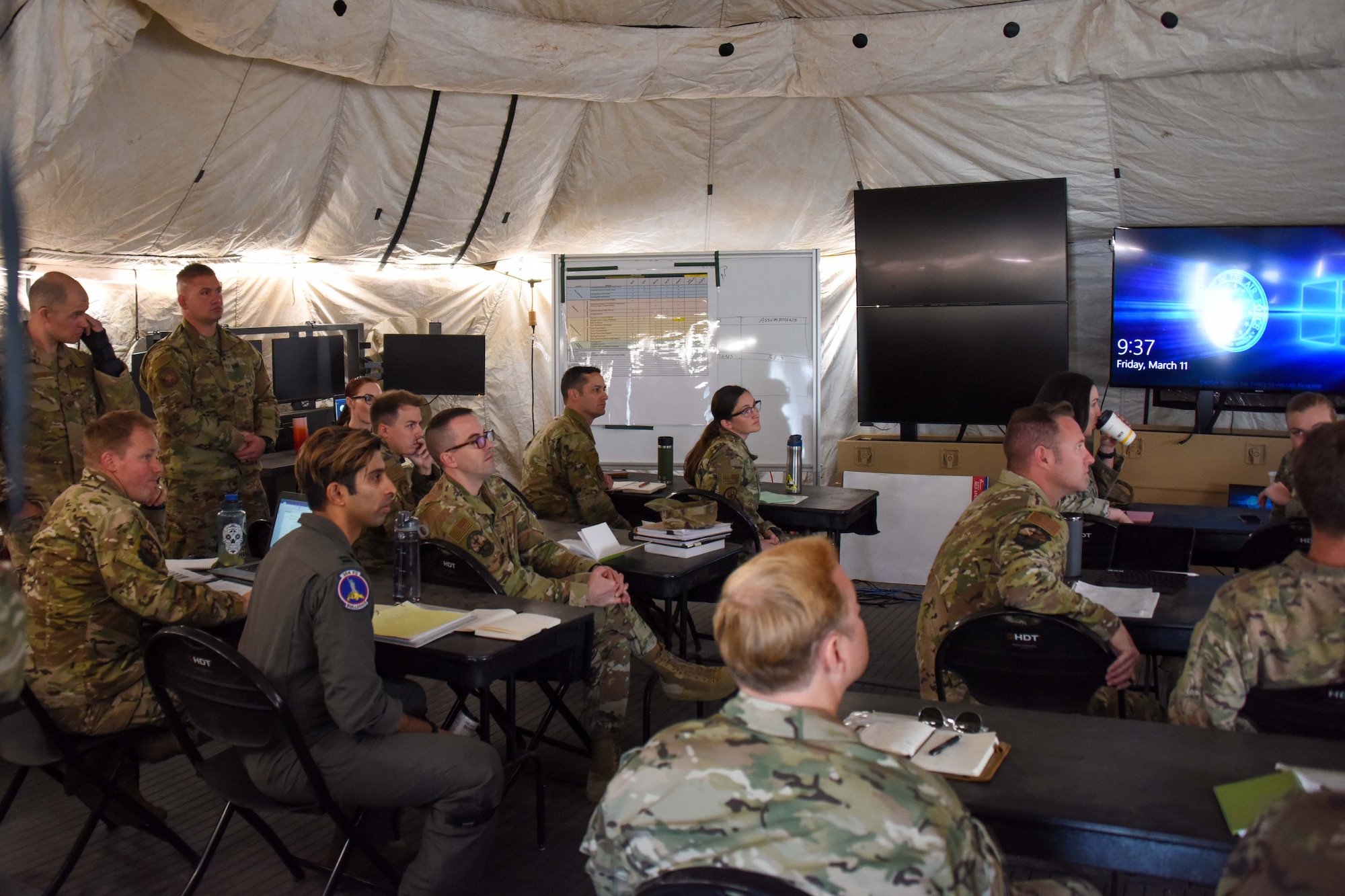 A photo of Airmen attending a briefing inside a command tent.