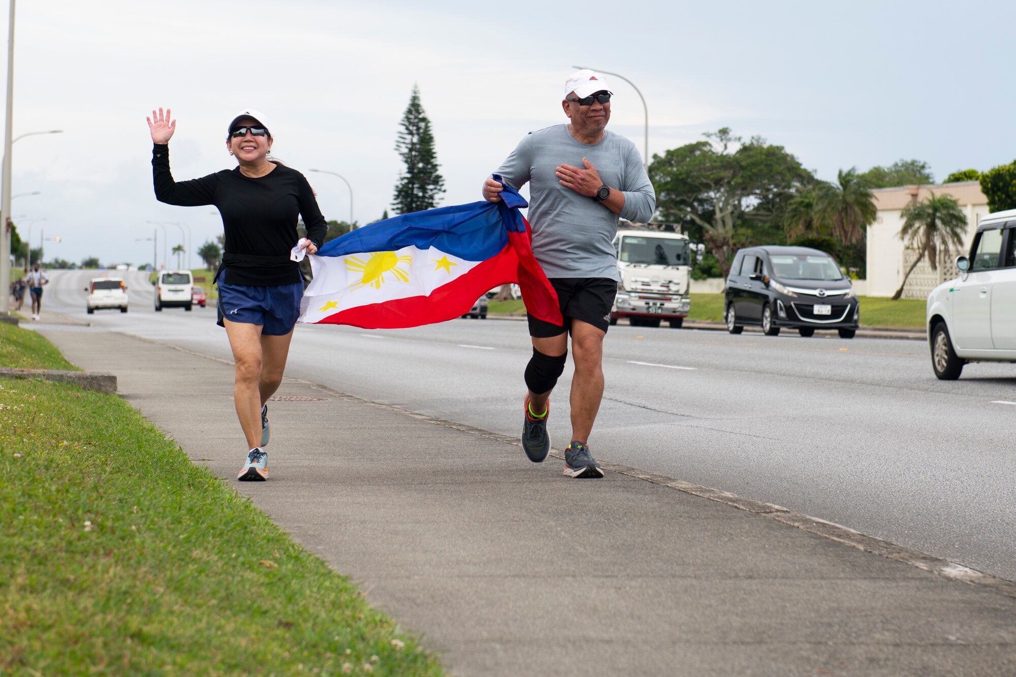 Runners cross the finish line displaying the Flag of the Philippines at the 9th Annual Memorial for the Bataan Death March at Kadena Air Base, Japan, April 23, 2022. The 8.5-mile run/ruck/walk was held to commemorate the American and Filipino servicemen who were marched nearly 70 miles to prison camps after surrendering at the Bataan Peninsula in April of 1942. (U.S. Air Force photo by Senior Airman Jessi Monte)