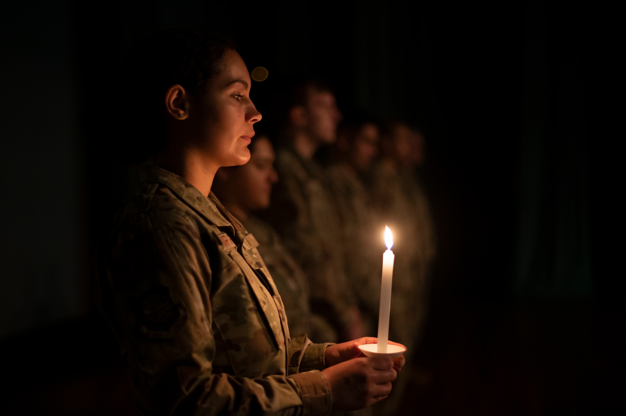 Airman Mireya Rico, 733rd Air Mobility Squadron aircraft services representative, holds a candle during a candlelight ceremony in honor of the Days of Remembrance at Kadena Air Base, Japan, April 29, 2022. Starting in 1939, Jewish people were forced to wear a yellow Star of David on their clothing, isolating them from the rest of society and making them easier to target. (U.S. Air Force photo by Senior Airman Jessi Monte)