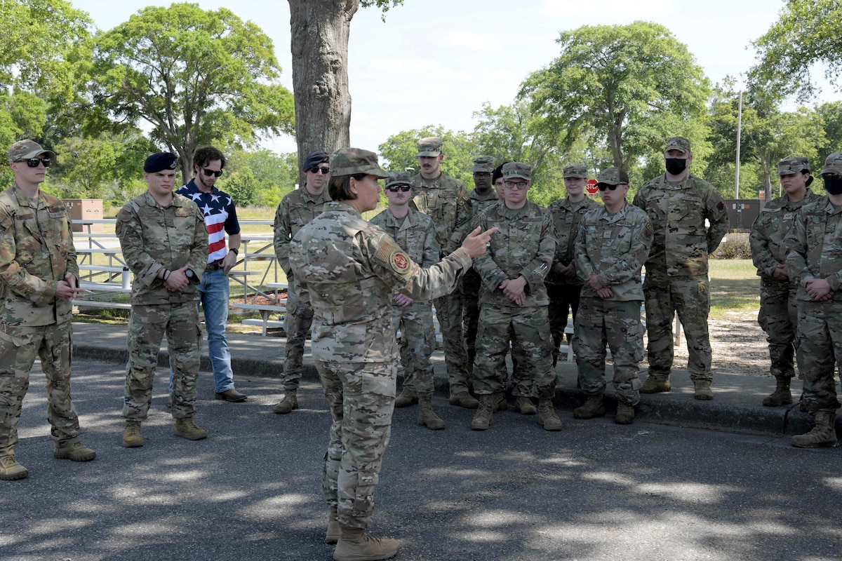 Airman speaking outside to a standing group of Airmen.