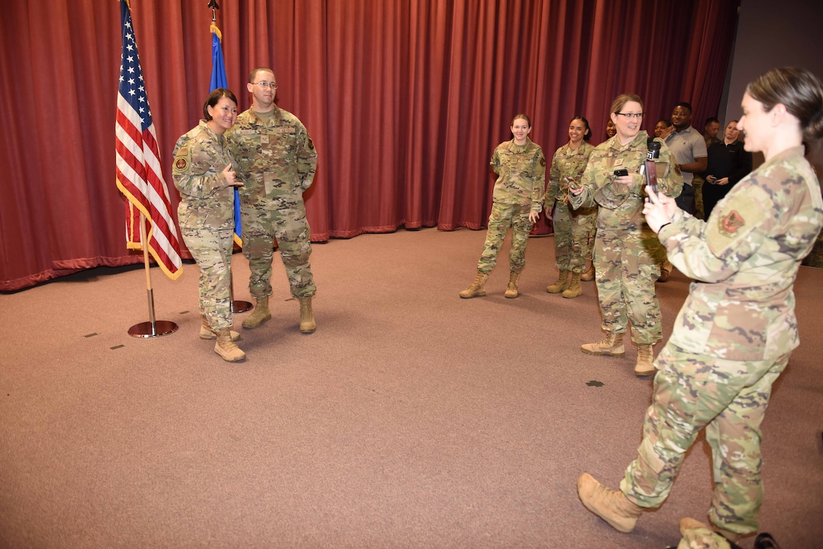 Two Airmen taking a photo together with another person taking the photo.