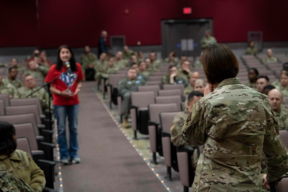 Airmen standing at mic addressing a person in an auditorium.