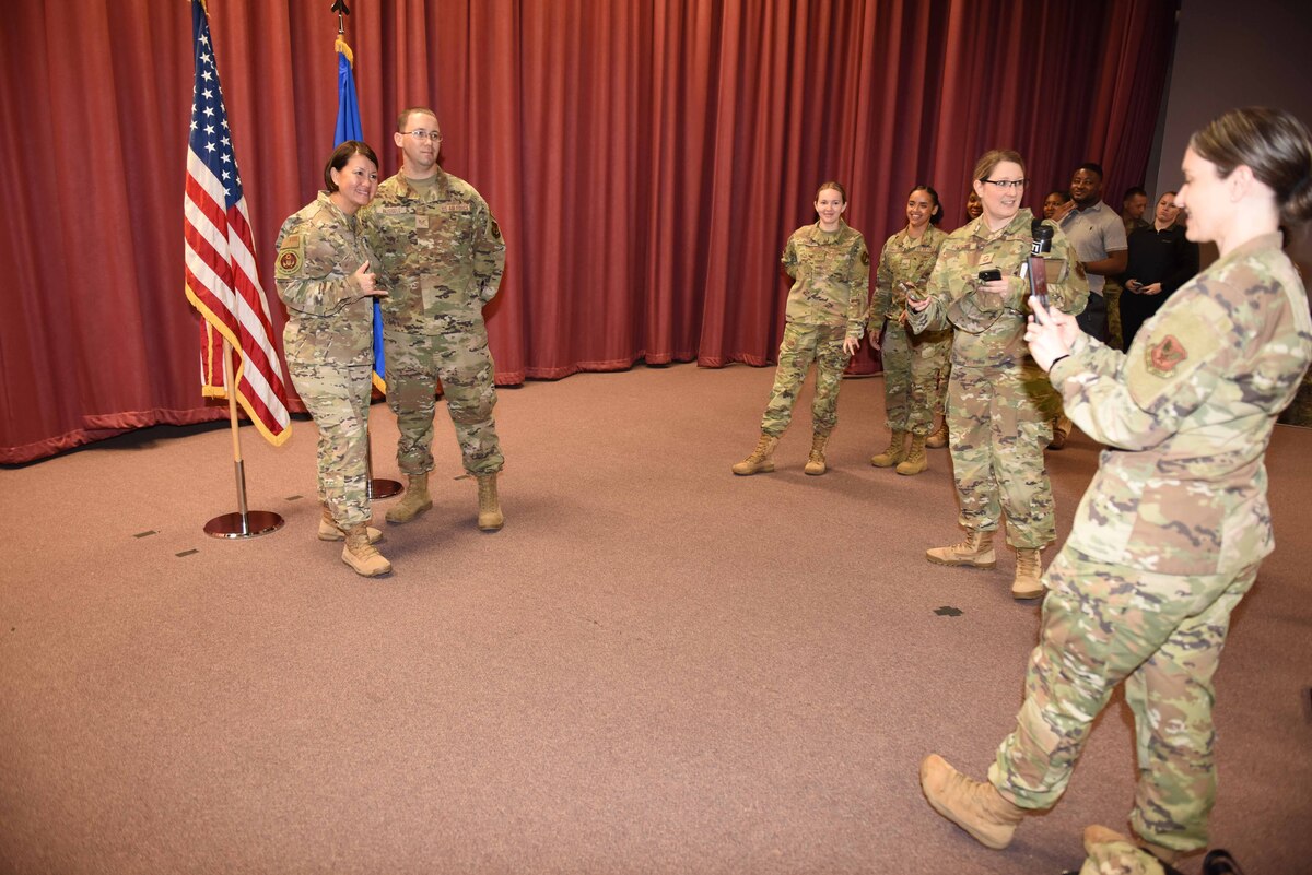 Two Airmen taking a photo together with another person taking the photo.