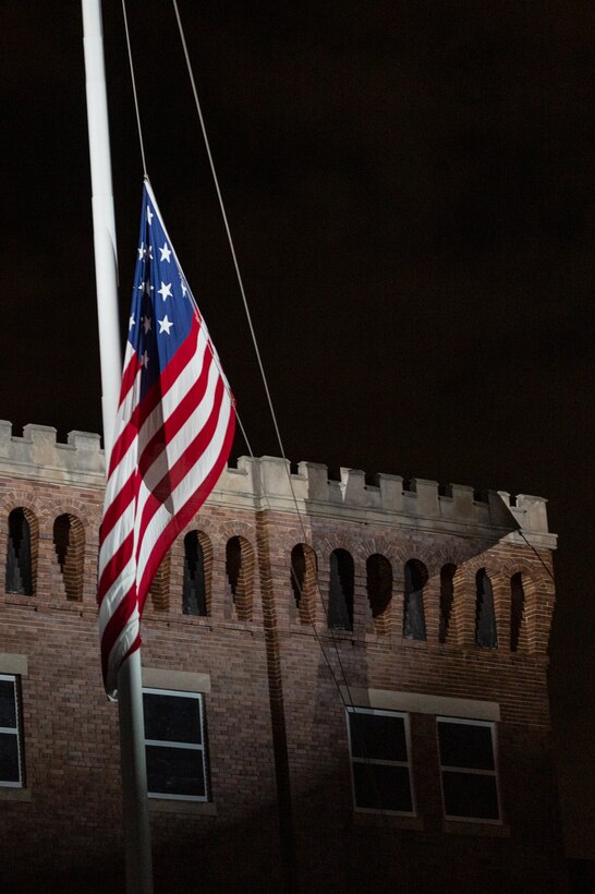 The flag is lowered over Marine Barracks Washington as the Marine Band performs Evening Colors during the 2022 full dress parade rehearsal.