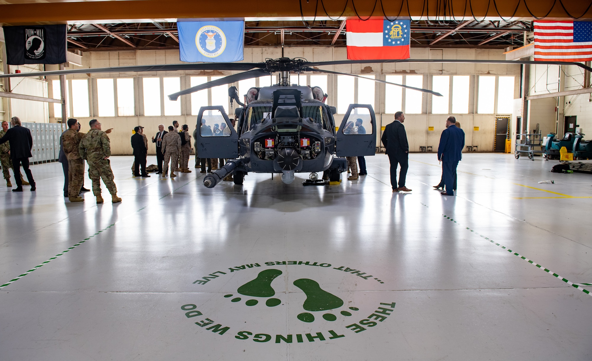 people standing around helicopter in a hangar
