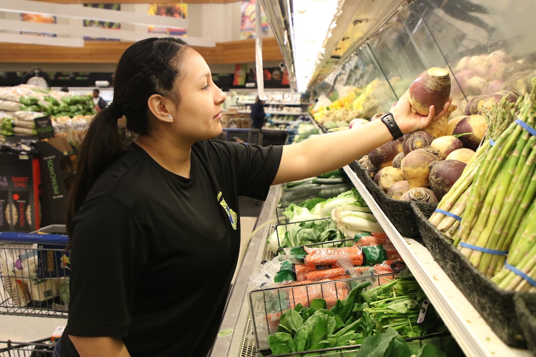 A soldier shops for vegetables.