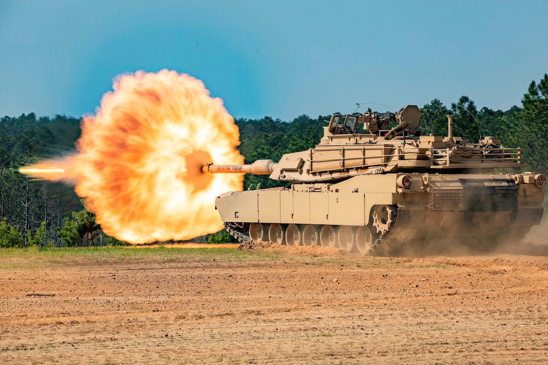 An armored vehicle fires in a field.