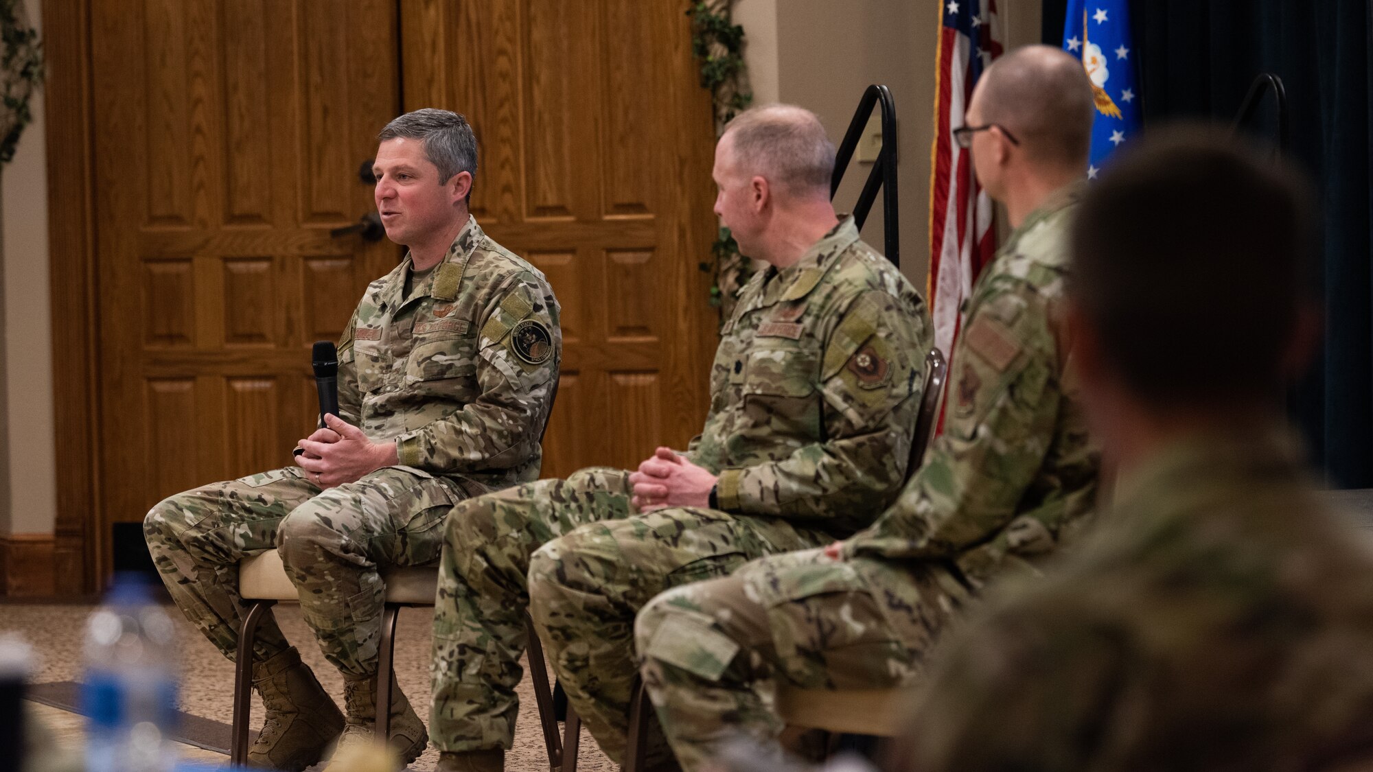 Airmen are sitting in front of a group of people.