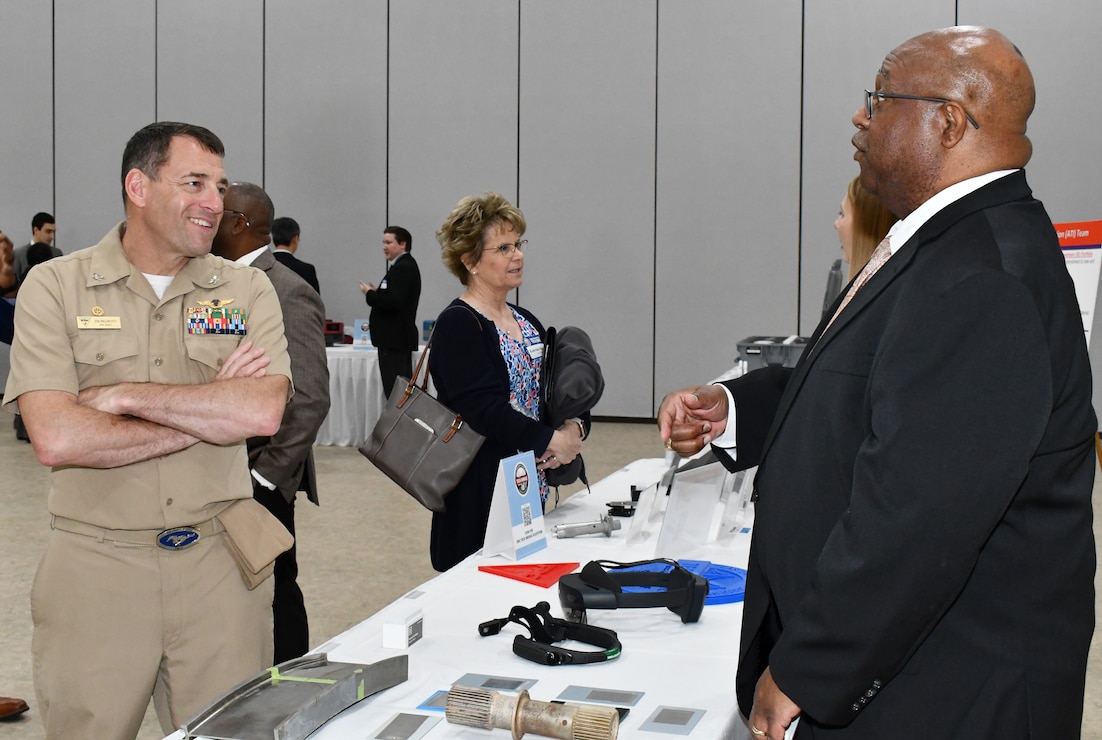 Navy officer and engineer hold discussion across expo table