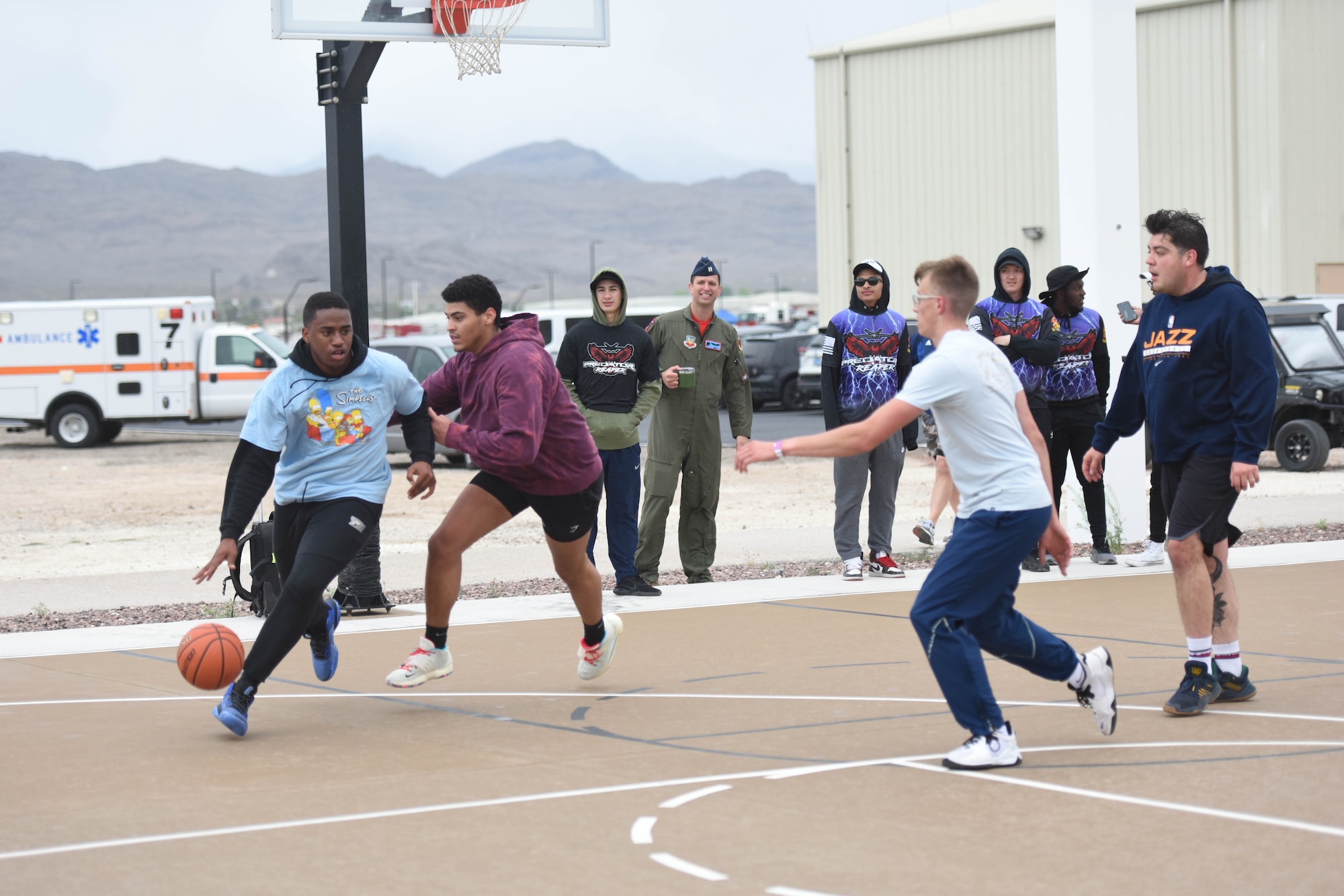 An airman dribbles a basketball past a defender during a basketball game.