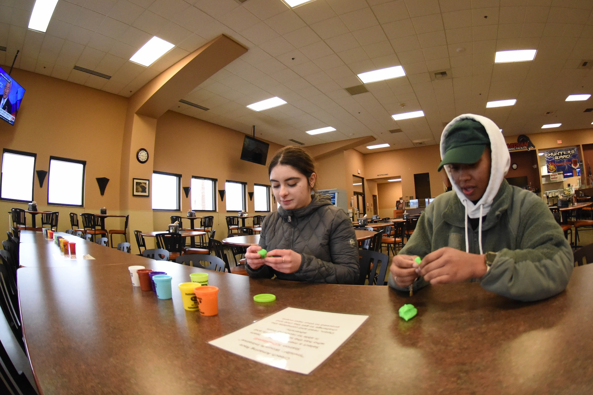 Two Airmen sit at a table with Play-Doh.