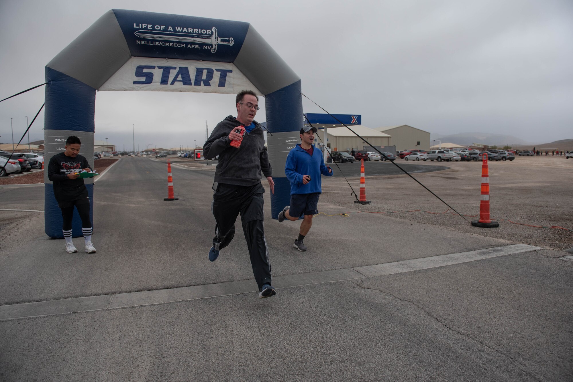 Two Airmen run past a finish line after finishing a 5K.