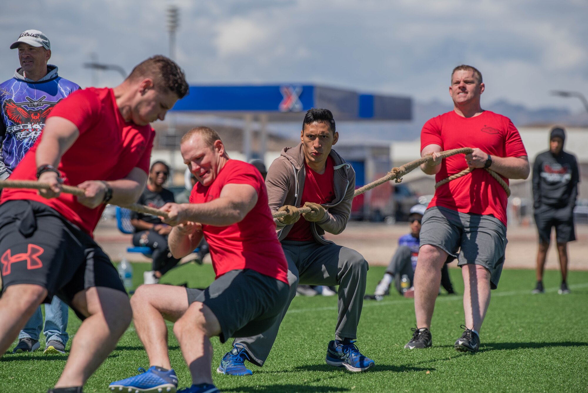 Four Airmen pull on a rope during a tug of war match on a turf field.