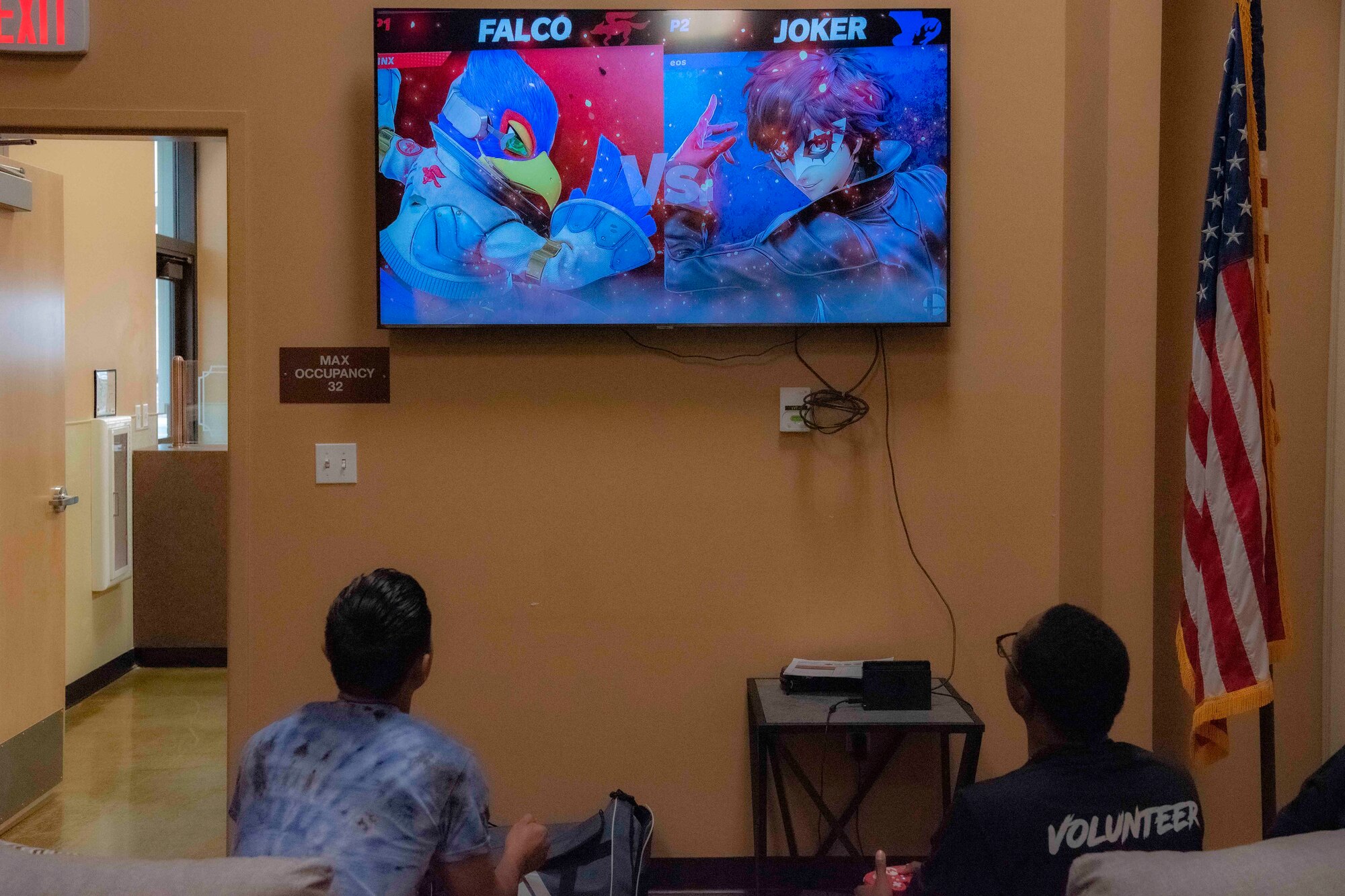 Two Airmen sit in front of a TV playing a video game.