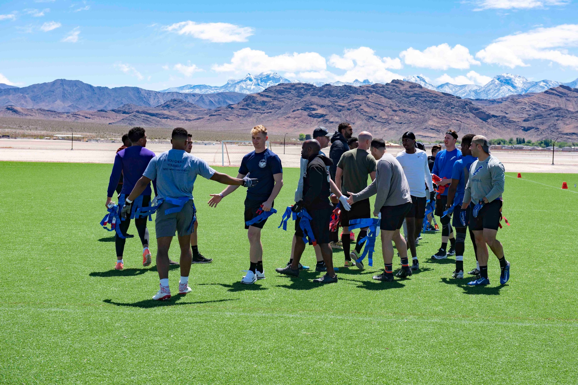 Airmen shake hands on a turf field after a football game.