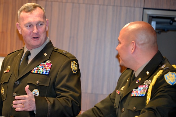 Two men in Army service dress speak to each other