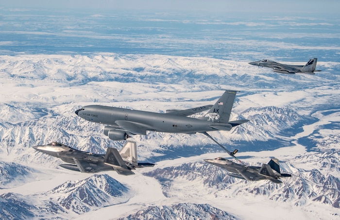 A KC-135 Stratotanker from the 168th Air Refueling Wing refuels F-22 Raptors from the 3rd Wing over the Joint Pacific Alaska Range Complex flying along side with an F-15 Eagles from the 144th Fighter Wing, April 18, 2022. The Eagles are training with the Raptors as part of Aslaska Dissimilar Aircraft Combat Training. (Air National Guard photo by Master Sgt. Charles Vaughn)