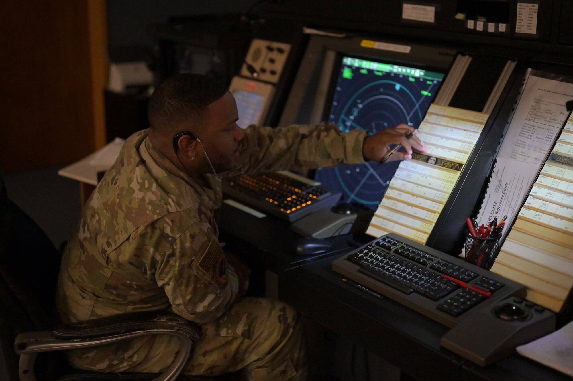 Airman sitting next to a radar screen.