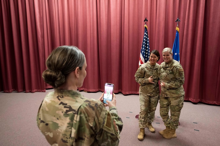 Airmen standing on stage posing for photo with another taking the photo.