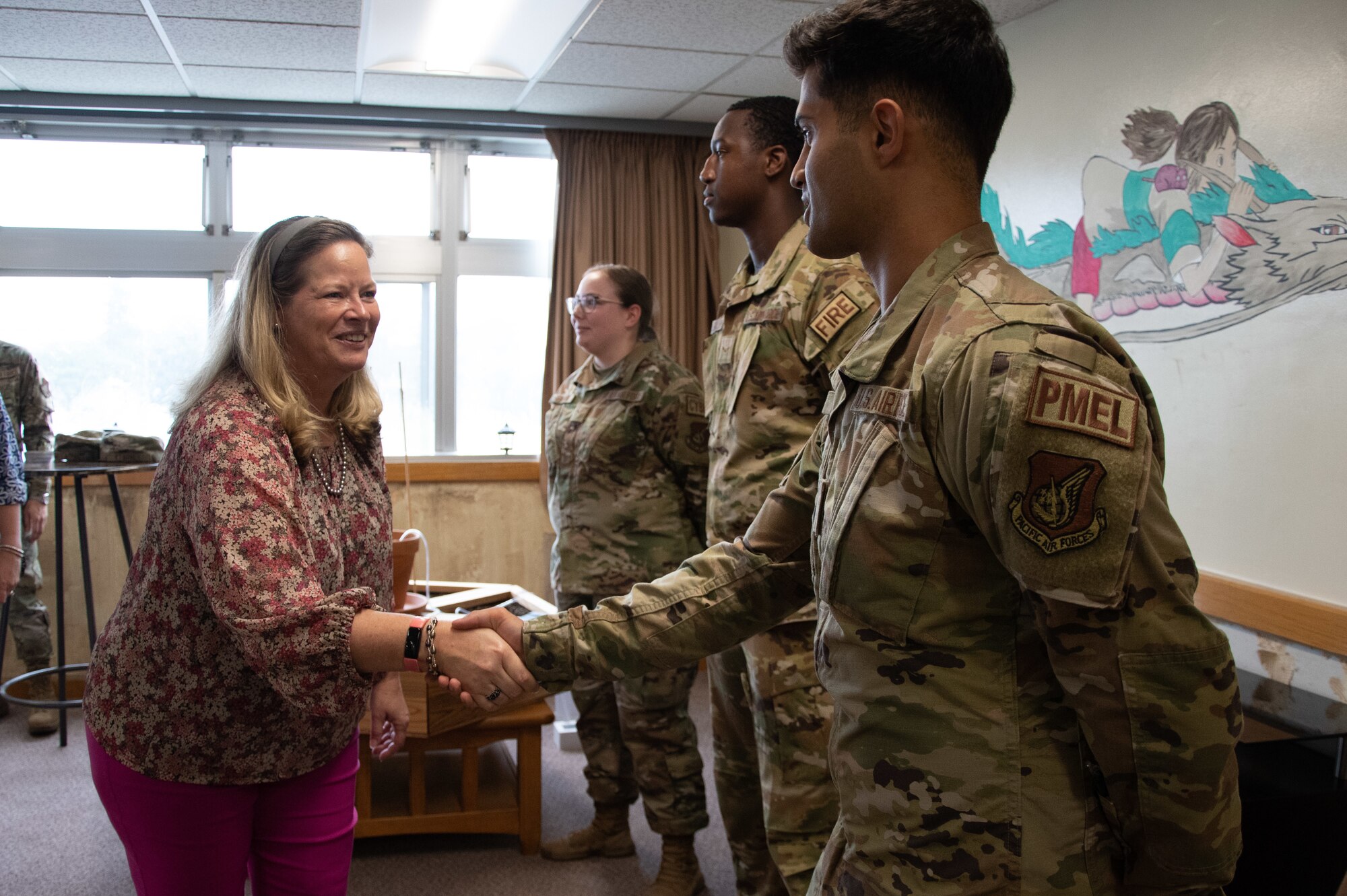 A woman shakes an Airman's hand