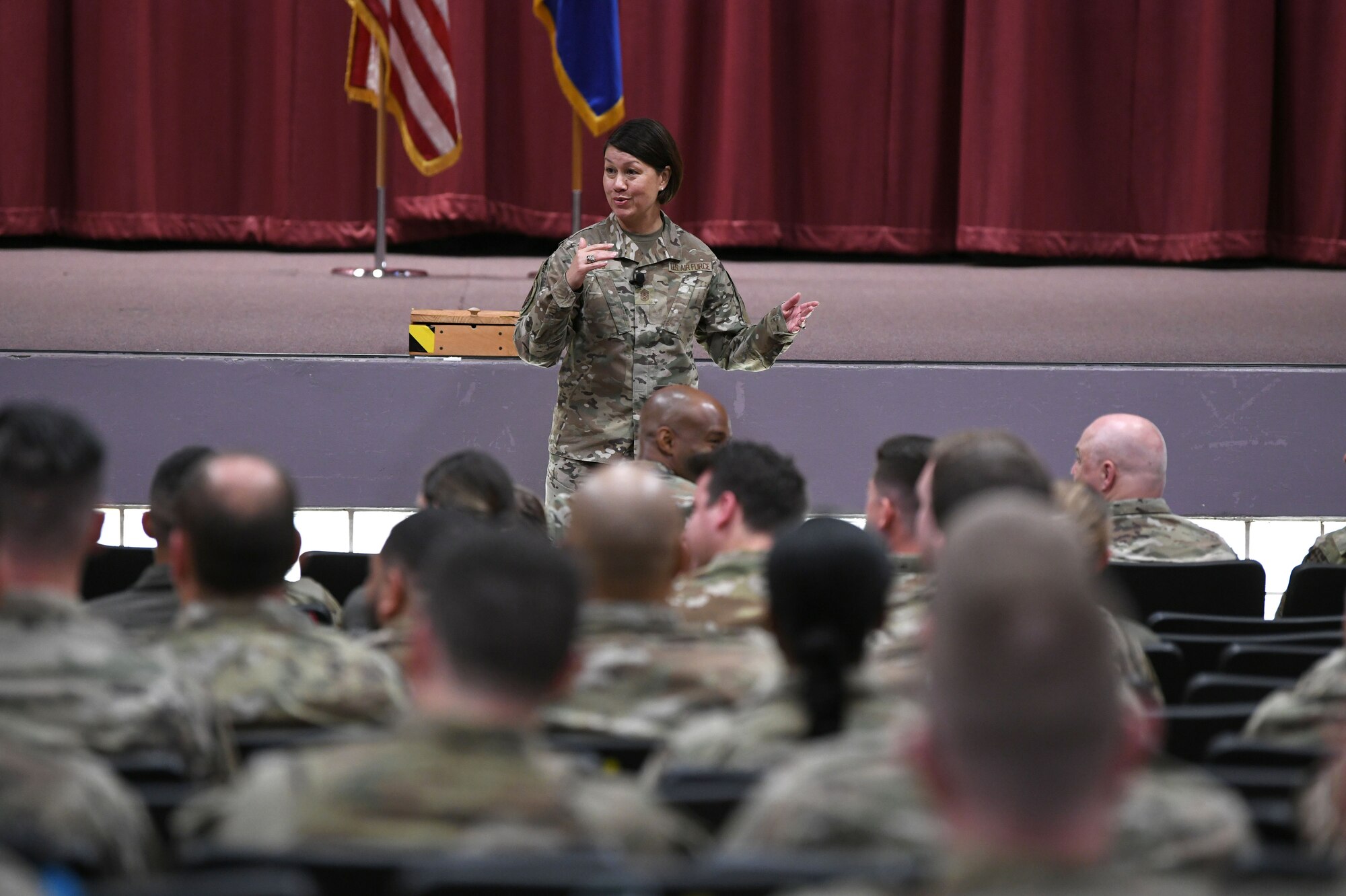 Airman speaking to an auditorium of people.