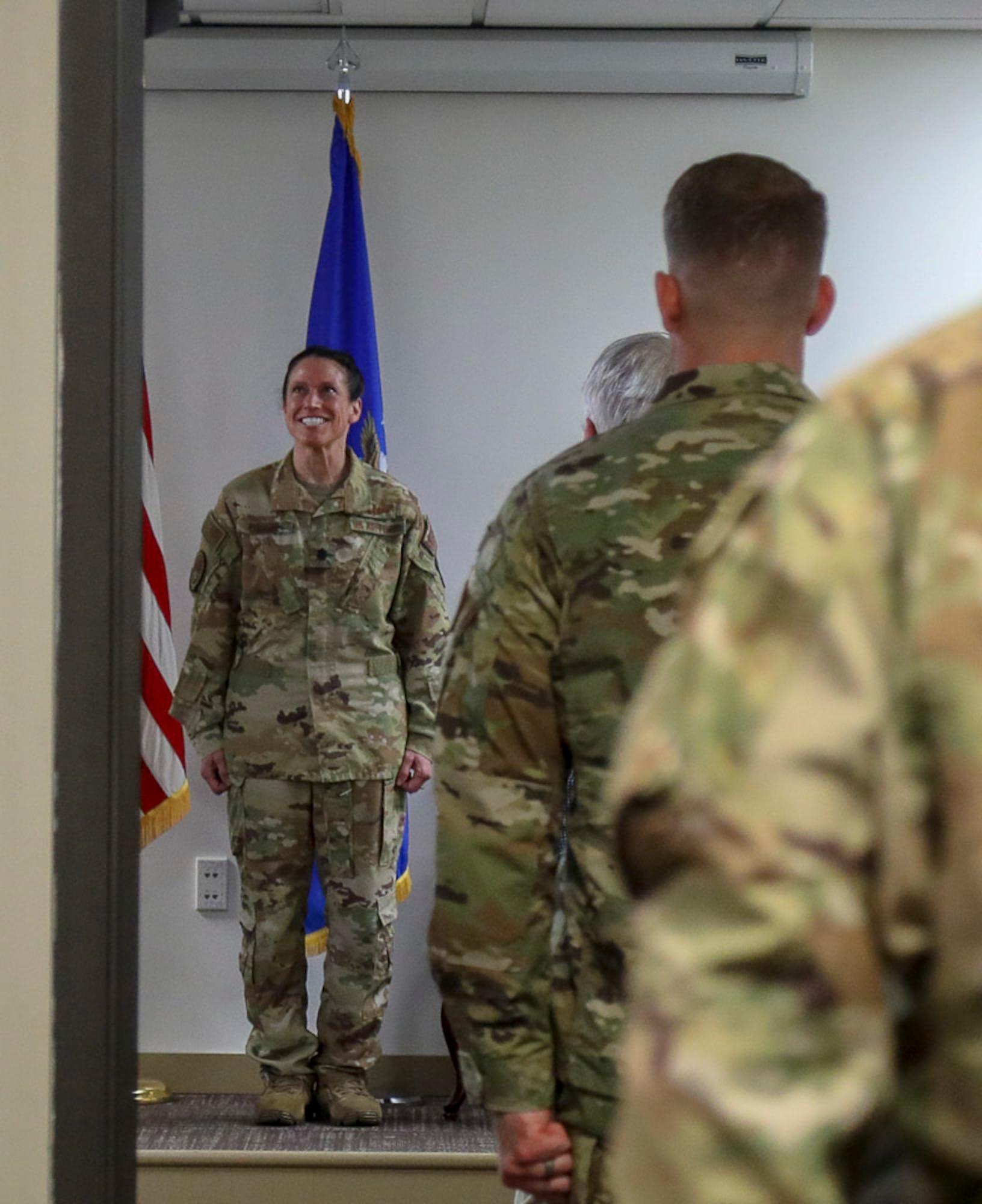 New AES commander smiles as Airmen stand at attention in an auditorium.