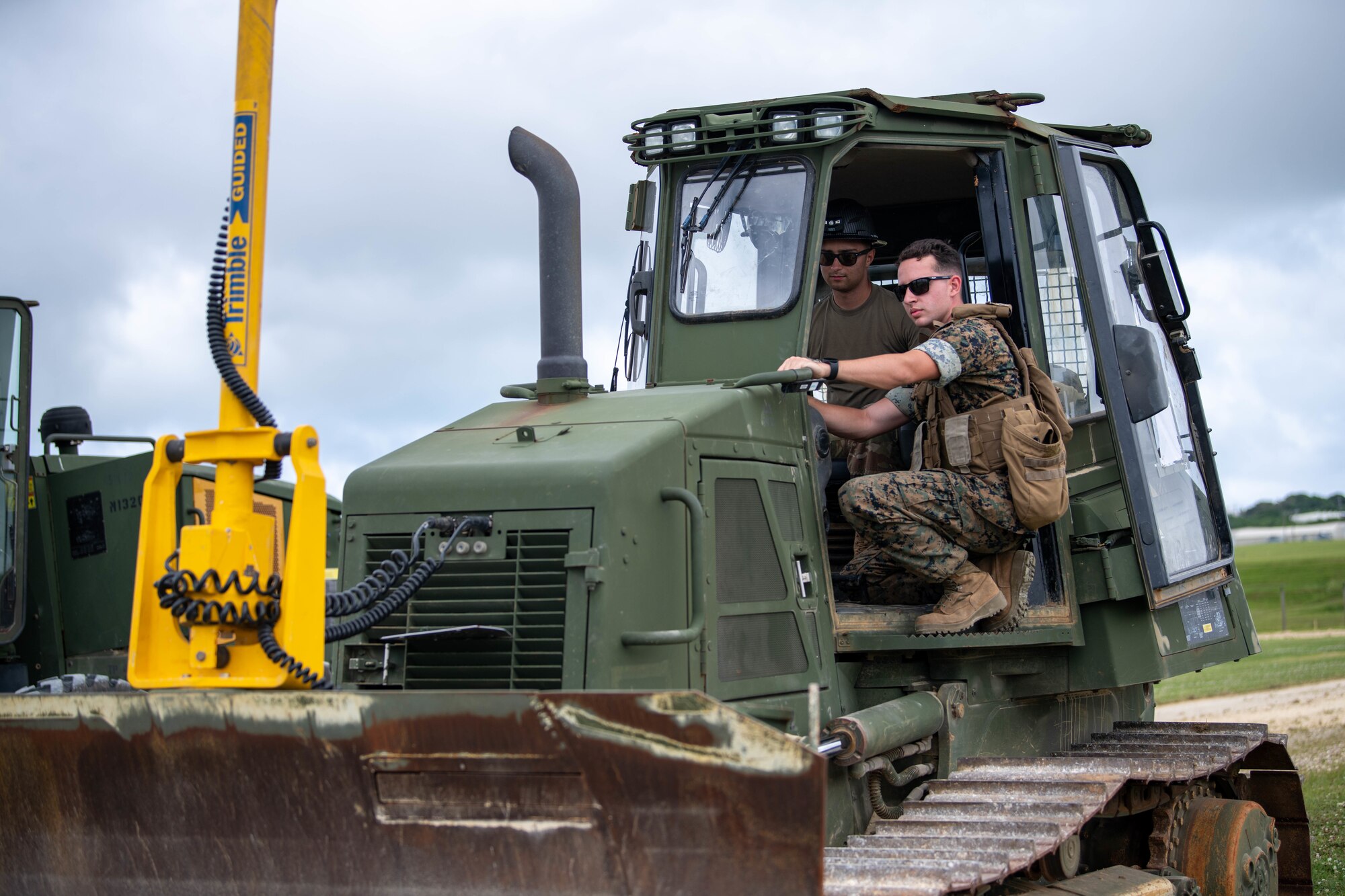 An Airman and a Marine use heavy equipment.