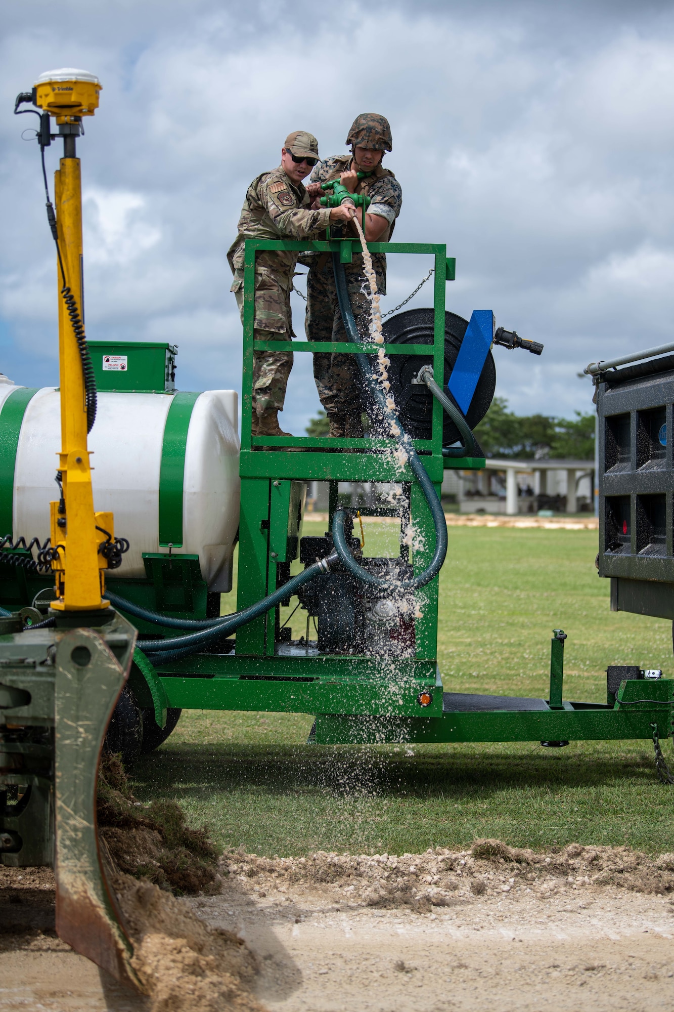 An Airman and a Marine use a water hose.