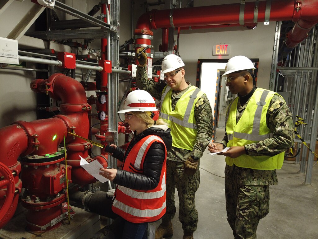 U.S. Army Corps of Engineers, Europe District Army Fellow Erin Dinunzio, Aegis Ashore Missile Defense System Poland Executive Officer Lt. Cmdr. Travis Avant and AAMDS Commanding Officer Cmdr. Joshua Wolf review working as-built drawings on the fire suppression system for accuracy and adequacy at the Aegis Ashore ballistic missile defense project April 1, 2022 in Redzikowo, Poland. As an Army Fellow with Europe District, Dinunzio is getting hands-on experience supporting projects in Europe. (Courtesy Photo)