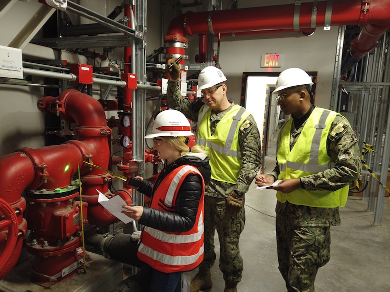 U.S. Army Corps of Engineers, Europe District Army Fellow Erin Dinunzio, Aegis Ashore Missile Defense System Poland Executive Officer Lt. Cmdr. Travis Avant and AAMDS Commanding Officer Cmdr. Joshua Wolf review working as-built drawings on the fire suppression system for accuracy and adequacy at the Aegis Ashore ballistic missile defense project April 1, 2022 in Redzikowo, Poland. As an Army Fellow with Europe District, Dinunzio is getting hands-on experience supporting projects in Europe. (Courtesy Photo)