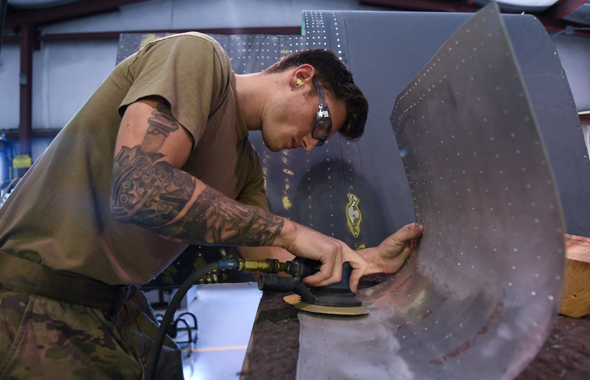 Senior Airmen Sean Olson, 920th Maintenance Squadron aircraft structural maintenance shop mechanic, scuff sands a sheet of metal; preparing it prior to applying a protective coating after an HC-130J Combat King II encountered a bird strike and required repairs at Patrick Space Force Base, Fla., April 19, 2022. (U.S. Air Force photo by Staff Sgt. Darius Sostre-Miroir)