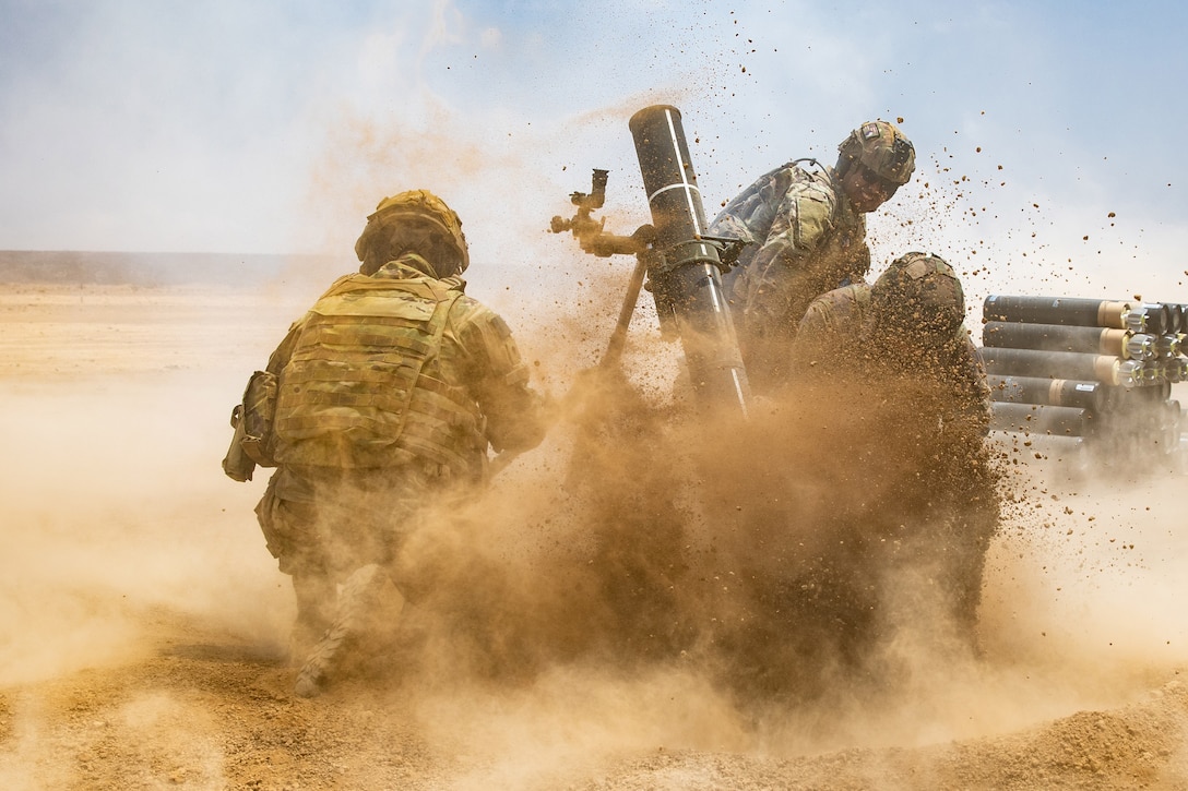 Dirt flies around as U.S. and French troops fire a weapon in a desert-like area.