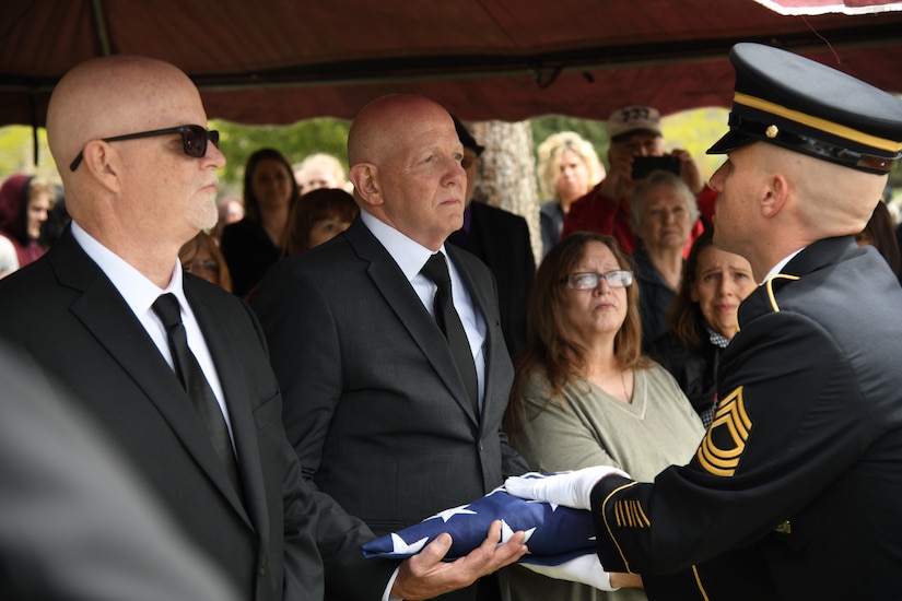 An honor guard soldier hands the American flag to the family of a deceased soldier.