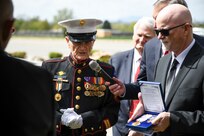 A veteran Marine gives a medal to family members of deceased Soldier.