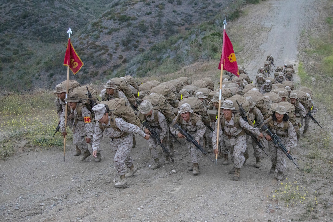 A group of Marines climb a hill.