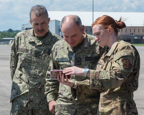 Staff Sgt. Kaitlin Cardello, 118th Airlift Squadron loadmaster, shows cell phone video of a Connecticut Air National Guard C-130H Hercules airdrop mission to Maj. Gen. Miguel Giordano, Uruguayan Army, and Col. Hugo Parentini, Uruguayan Air Force, during a State Partnership Program visit to Bradley Air National Guard Base, East Granby, Conn. Aug. 15, 2019. Connecticut and Uruguay are celebrating 20 years of partnership through SPP, a nationwide program the National Guard established in 1993 to promote enduring and mutually beneficial security relationships with ally nations. (U.S. Air National Guard photo by Staff Sgt. Steven Tucker)