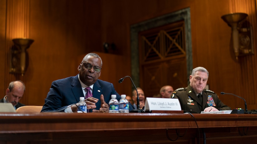 Two men speak from a table.