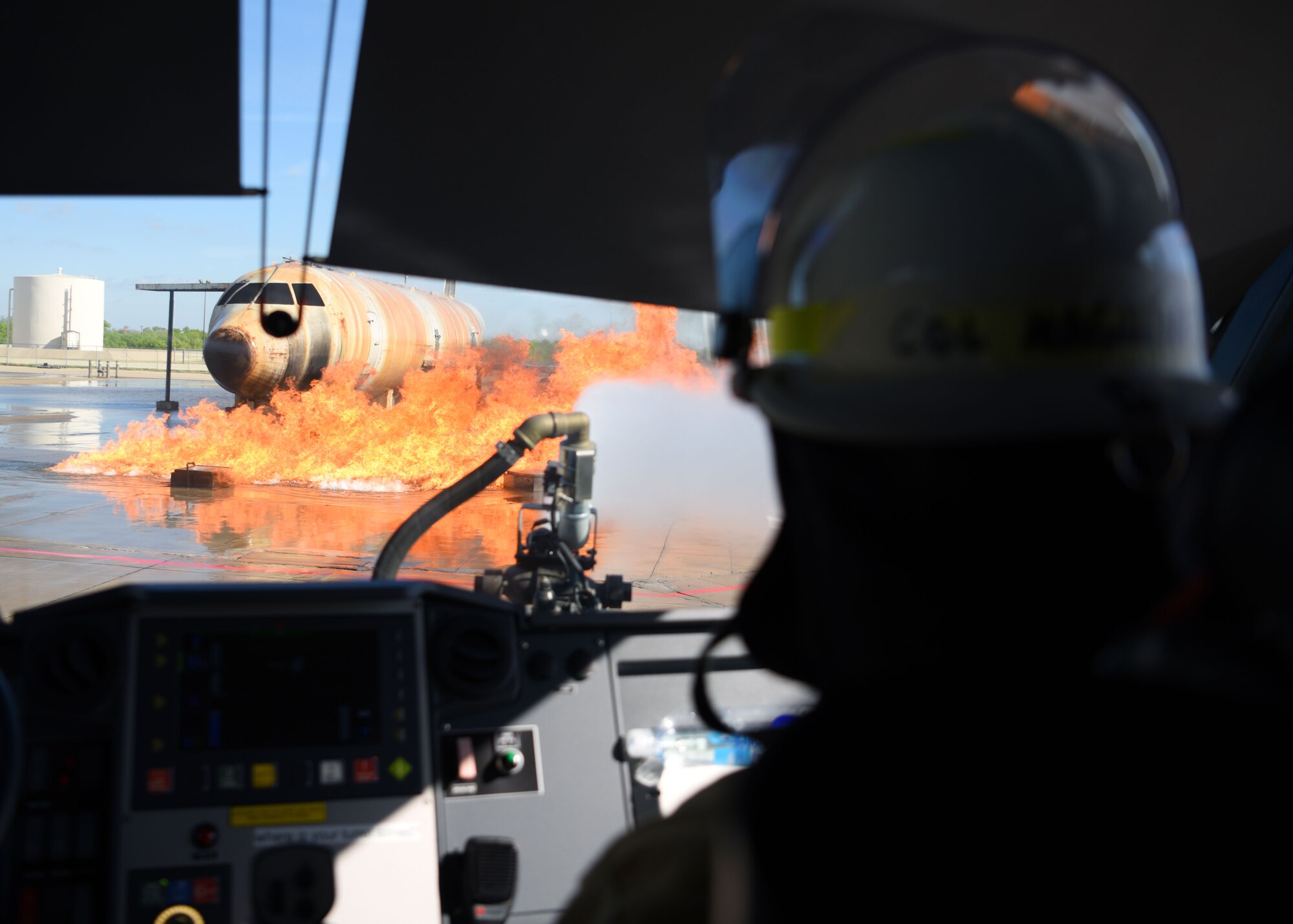 U.S. Air Force Col. Angelina Maguinness, 17th Training Group commander, uses a firetruck to extinguish an aircraft fire at the Louis F. Garland Department of Defense Fire Academy, Goodfellow Air Force Base, Texas, April 20, 2022. Fire marshals used trucks as well as hoses to extinguish fires and complete their objectives. The Fire Marshal course was designed to provide insight on the numerous responsibilities and challenges within Department of Defense Fire and Emergency Services to future civil engineer commanders. (U.S. Air Force photo by Senior Airman Ethan Sherwood)