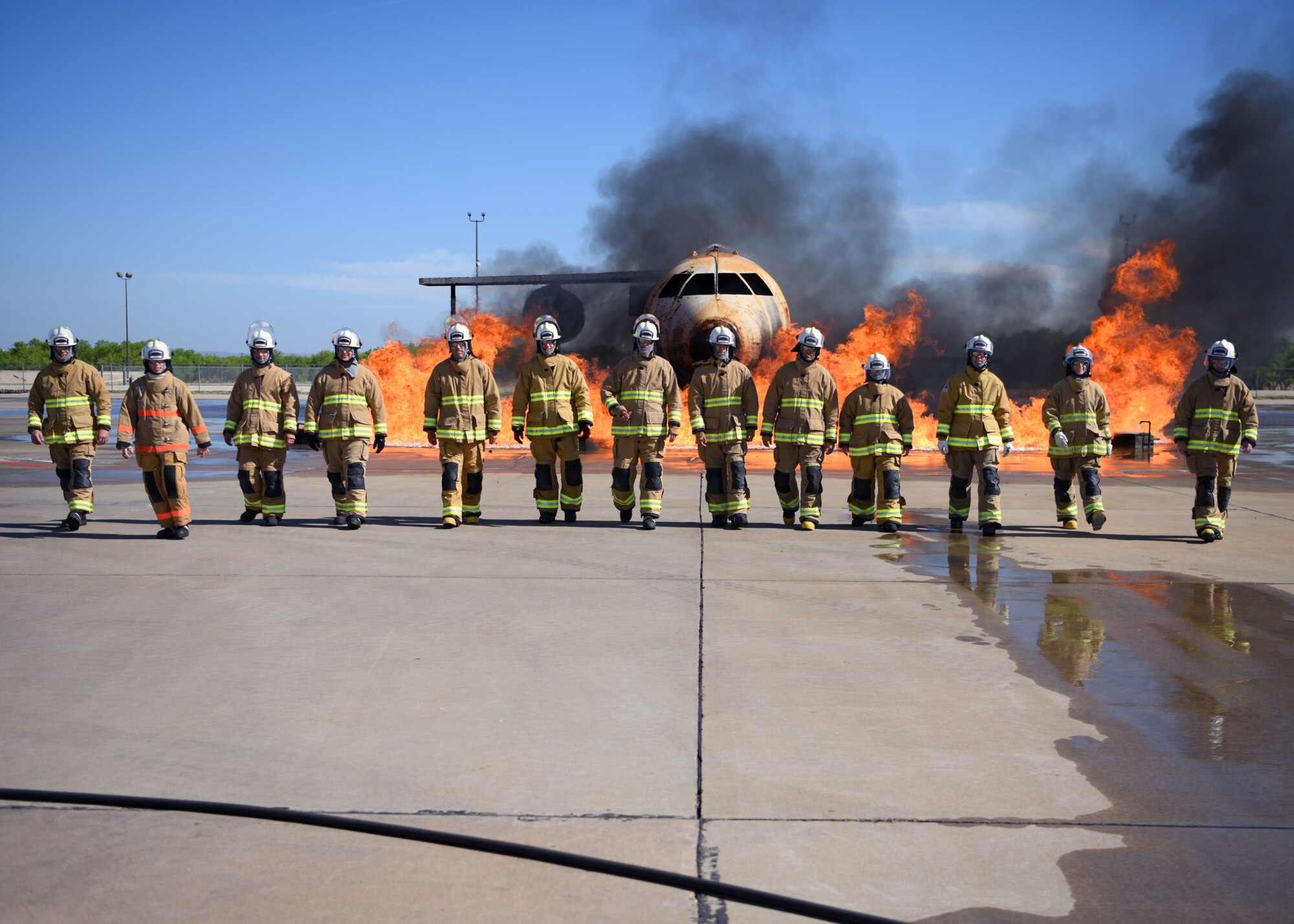 Fire marshals walk away from an aircraft fire trainer after completing each exercise during their Fire Marshal course at the Louis F. Garland Department of Defense Fire Academy, Goodfellow Air Force Base, Texas, April 20, 2022. After completing the three-day course, students gained the fire marshal certification. The Fire Marshal course was designed to provide insight on the numerous responsibilities and challenges within Department of Defense Fire and Emergency Services to future civil engineer commanders. (U.S. Air Force photo by Senior Airman Ethan Sherwood)