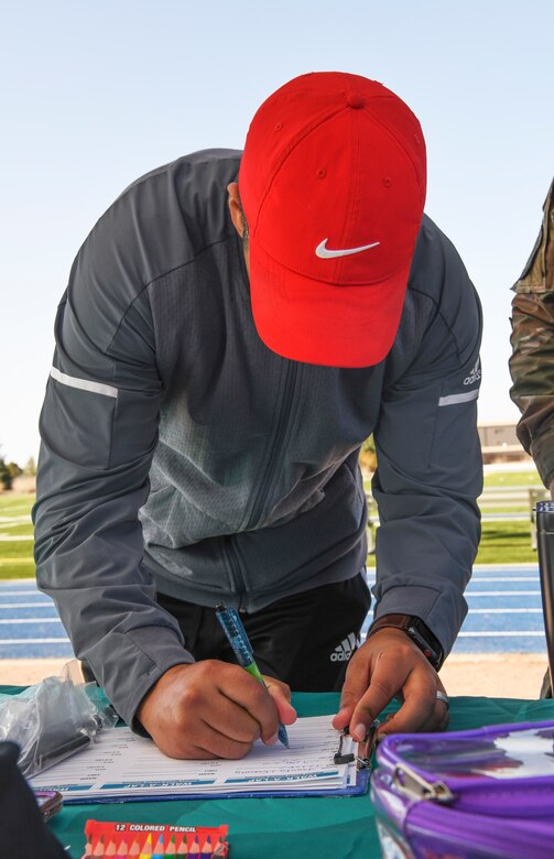 Man in red hat writes his name on clipboard