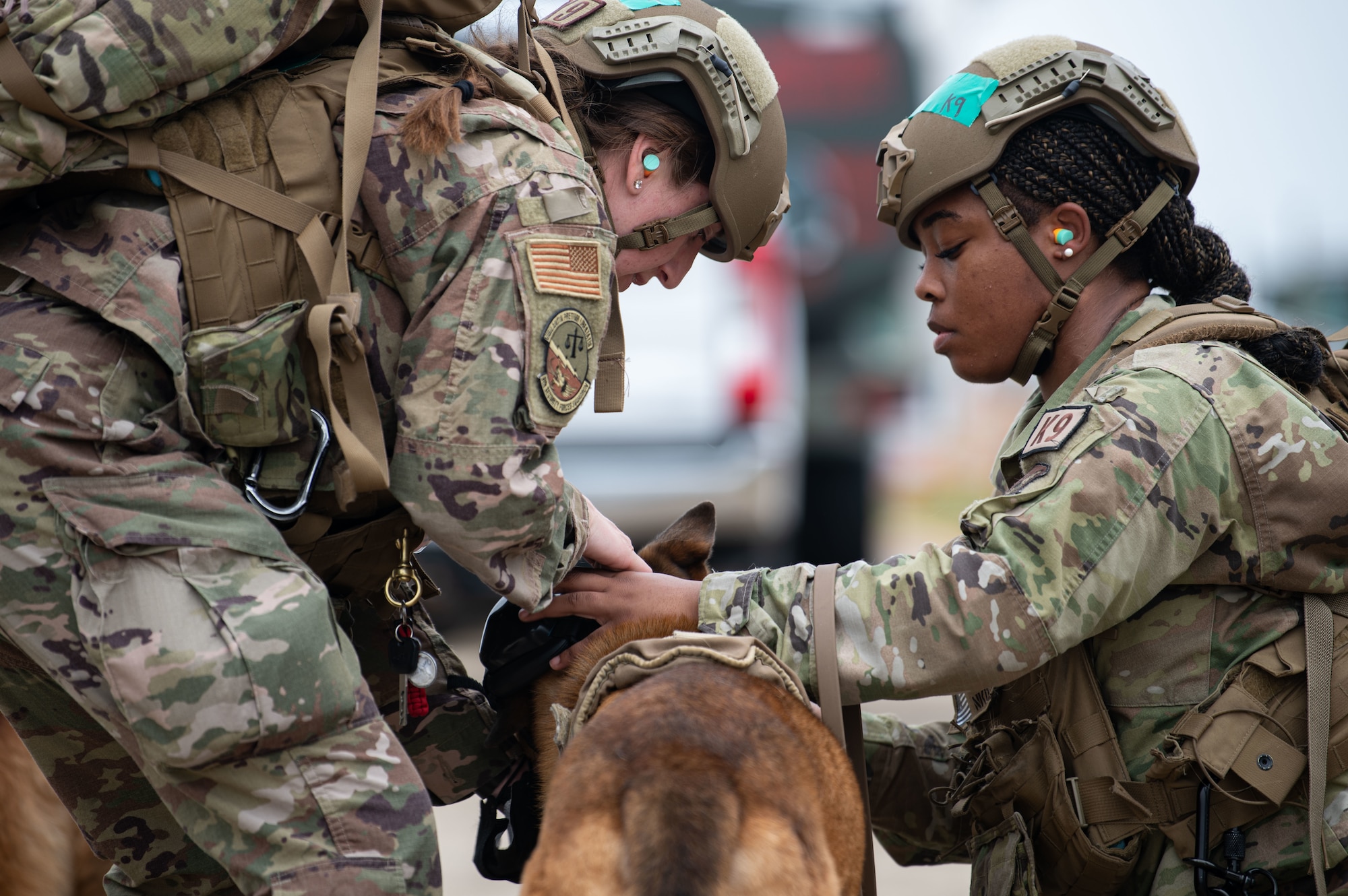Staff Sgt. Darby Misner, 8th Security Forces Squadron military working dog (MWD) trainer, left, MWD Bonus, center, and Senior Airman Tyyori Major, 8th Security Forces Squadron military working dog handler, right, position hearing protection on MWD Bonus prior to K-9 medical evacuation training at Kunsan Air Base, Republic of Korea, April 26, 2022. These trainings not only benefit the MWDs, but also helps the handlers, veterinary staff, aviation brigade personnel, and the 8th Medical Group reevaluate and develop processes for continuity and quick action responses in emergency scenarios. (U.S. Air Force photo by Staff Sgt. Gabrielle Spalding)
