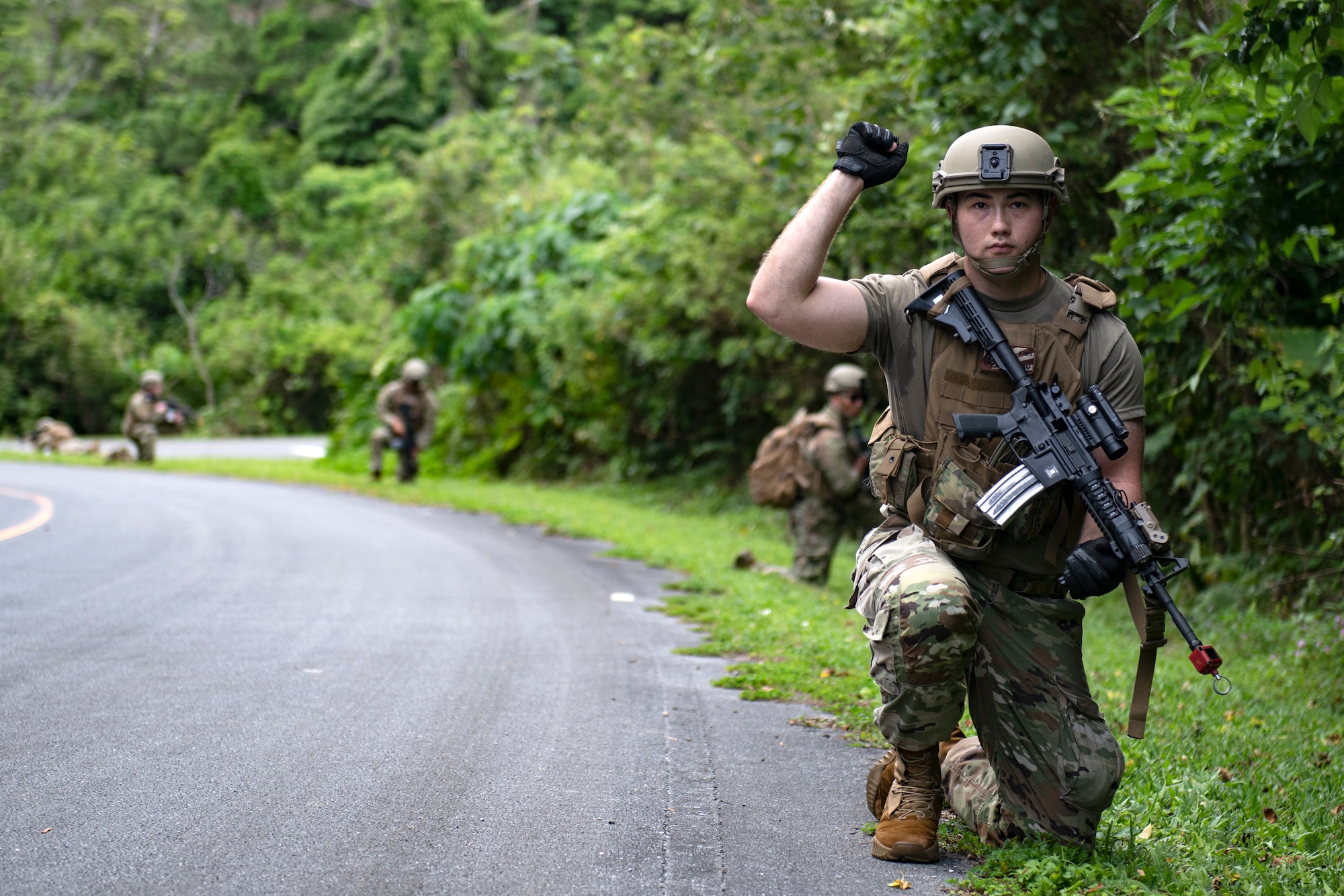 A U.S. Air Force Airman assigned to the 18th Security Forces Squadron gives his group the signal to halt during a field training exercise at Kadena Air Base, Japan, April 27, 2022. Visual signals are a means of communication that can be used to transmit prearranged messages over short distances when maintaining silence or stealth is necessary. (U.S. Air Force photo by Senior Airman Jessi Monte)