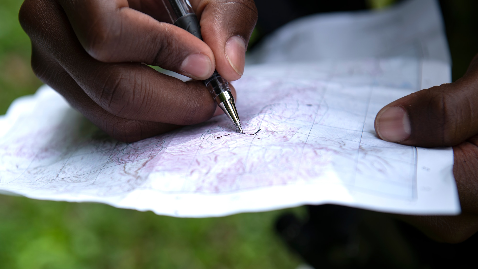 A U.S. Air Force Airman assigned to the 18th Security Forces Squadron marks a location on a map during a field training exercise at Kadena Air Base, Japan, April 27, 2022. Land navigation is a critical skill for SFS Airmen, utilizing maps with reference to terrain, a compass and other vital navigation tools. (U.S. Air Force photo by Senior Airman Jessi Monte)