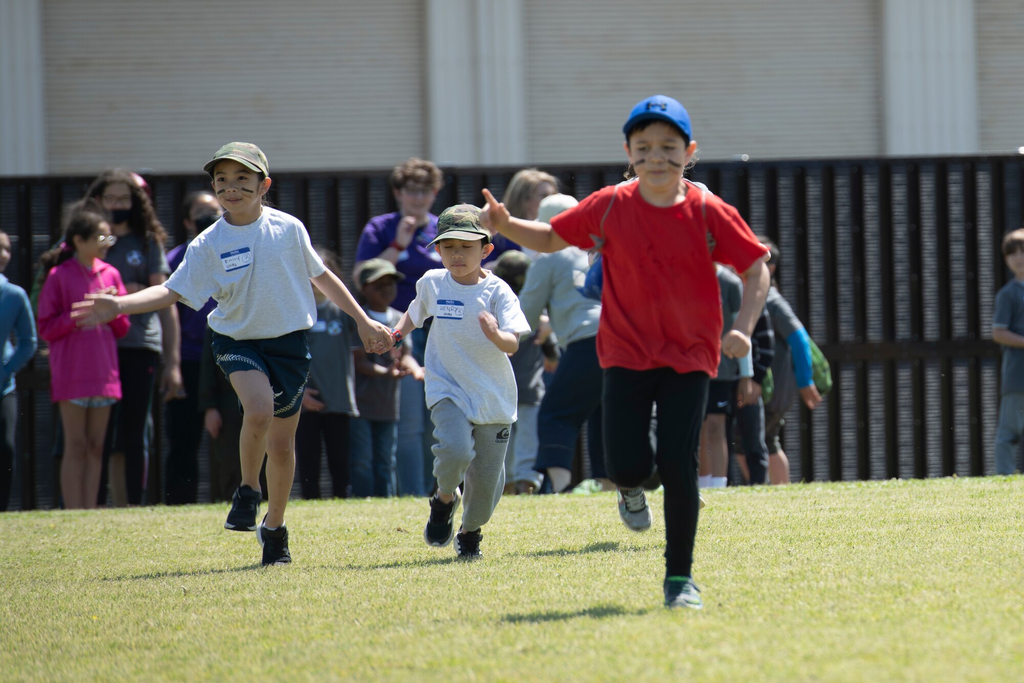 Emily, right, and Henry Valdez, middle, race against Julian Dickson, Operation Kids Understanding Deployment Operations participants, during Operation K.U.D.O.S. at Yokota Air Base, Japan, April 30, 2022. During Operation K.U.D.O.S., children performed a variety of deployment like exercises to help gain a knowledge of the setting their family may face. (U.S. Air Force photo by Tech. Sgt. Joshua Edwards)