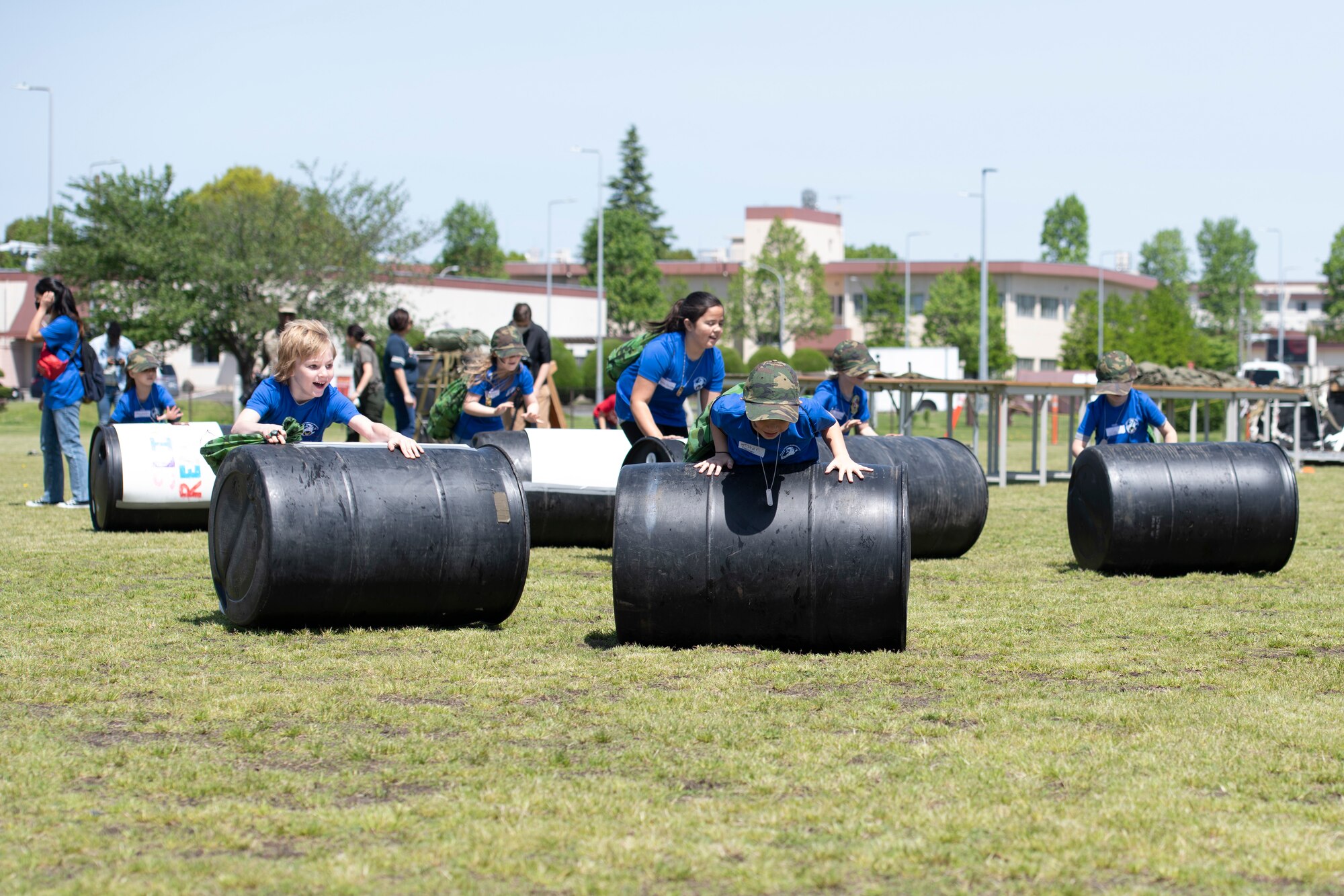 Operation Kids Understanding Deployment Operations participants roll barrels as part of Operation K.U.D.O.S. at Yokota Air Base, Japan, April 30, 2022. Operation K.U.D.O.S. consisted of pre-deployment processing and mock deployment scenario to help children understand what it is like for their parent to deploy. (U.S. Air Force photo by Tech. Sgt. Joshua Edwards)