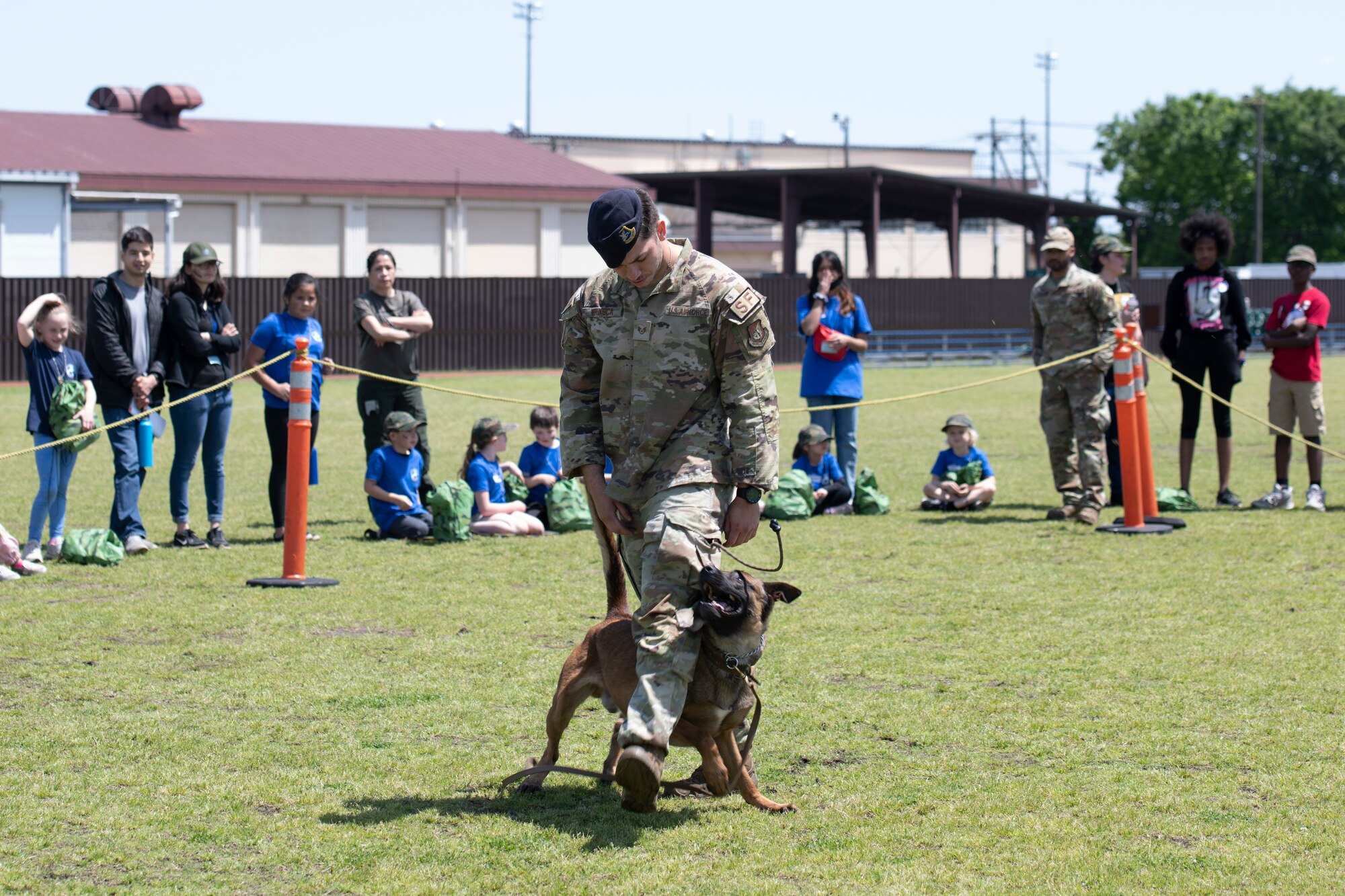 Staff Sgt. Marcello Frasca, 374th Security Forces Squadron military working dog handler, and Rroswell, MWD, perform a demonstration during Operation Kids Understanding Deployment Operations at Yokota Air Base, Japan, April 30, 2022. During Operation K.U.D.O.S., children performed a variety of deployment like exercises to help gain a knowledge of the setting their family may face. (U.S. Air Force photo by Tech. Sgt. Joshua Edwards)